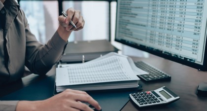 A man studies a computer screen with figures on
