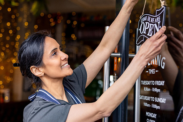 Smiling Women Turning Cafe Door Sign To Open
