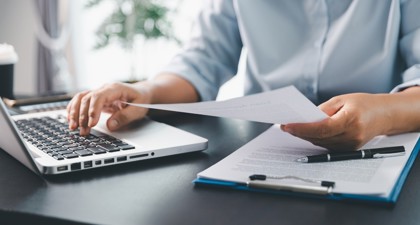 Close up of a man's hands using his laptop to file his tax return