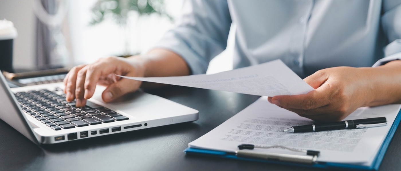 Close up of a man's hands using his laptop to file his tax return